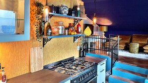 A modern kitchen with a gas stove, wooden shelves, and a blue accent wall. - Casa Olanda (mornico losana)