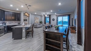 A modern kitchen with dark cabinets, a central island, and a dining area with a wooden table and chairs. - Peaceful Location w/Sunset & Wildlife Views, Htd Pool, Hot Tub, Fire Table, 2 Bikes (Gold Canyon)