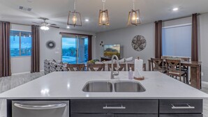 A modern kitchen with a large island, stainless steel sink, and pendant lighting. - Peaceful Location w/Sunset & Wildlife Views, Htd Pool, Hot Tub, Fire Table, 2 Bikes (Gold Canyon)