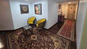 A hallway with a patterned carpet, two yellow chairs, and two framed artworks on the wall. - Amazônia Studio: experience the essence of the region (Belém)