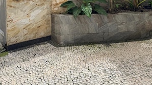 A building facade with a stone wall, a sign reading '1185 ED. AUGUSTUS,' and a planter with tropical plants. - Amazônia Studio: experience the essence of the region (Belém)