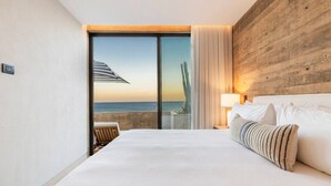 Habitación de hotel con una cama grande, vista al mar y una pared de madera decorativa.