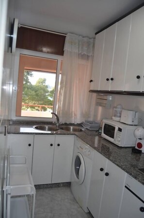 Een koelkast, een microgolfoven, kookgerei, borden en bestek