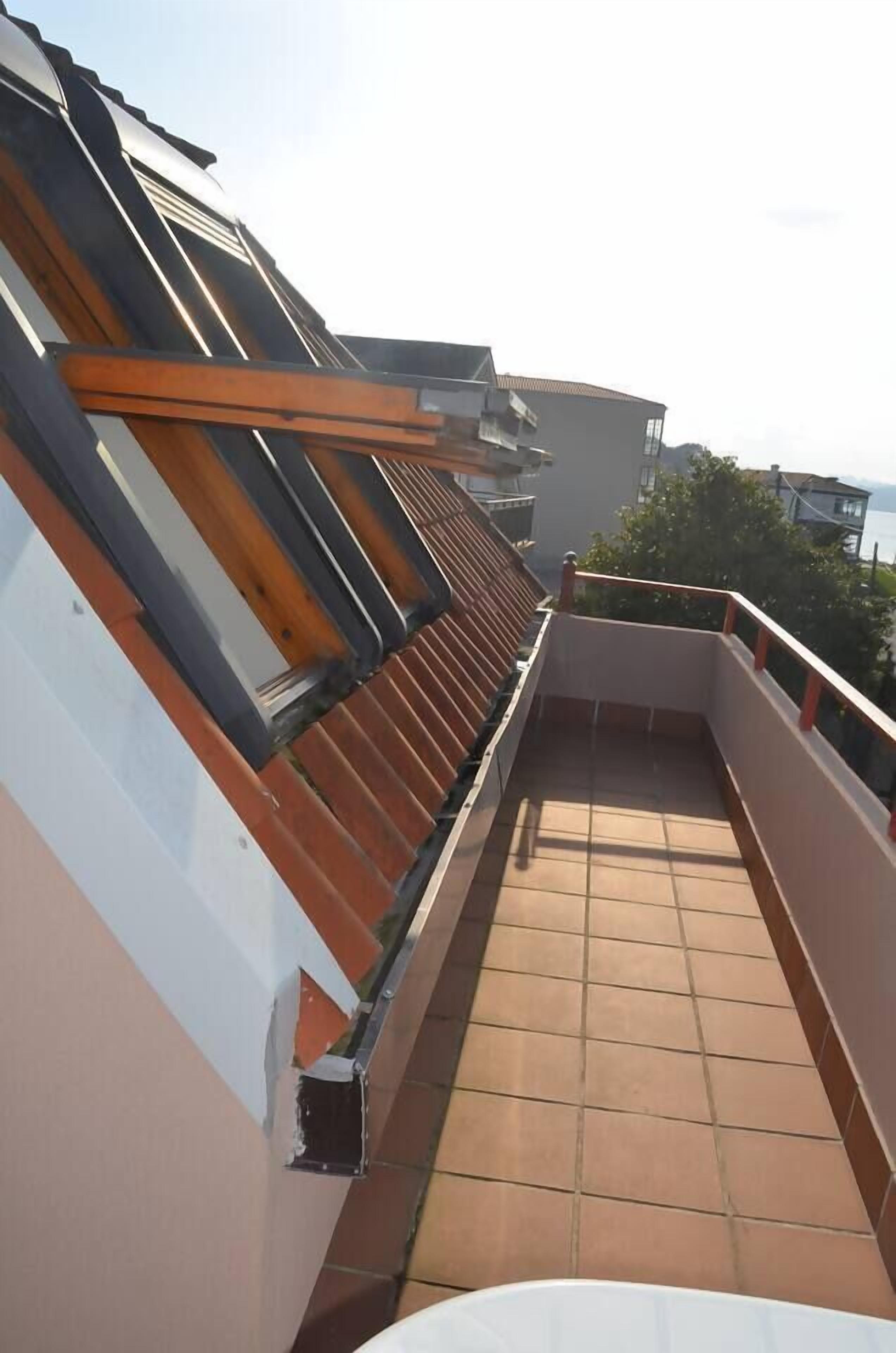A rooftop terrace with a tiled floor and a wooden railing.