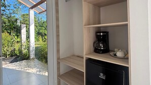 Eine kompakte Küche mit einem eingebauten Kühlschrank, einer Kaffeemaschine und einer Glastür, die auf eine Außenpatio führt.