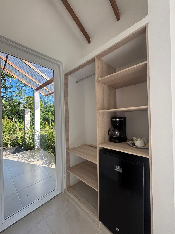 A compact kitchen with a built-in refrigerator, a coffee maker, and a glass door leading to an outdoor patio. - Valle de Angeles (Guamal)