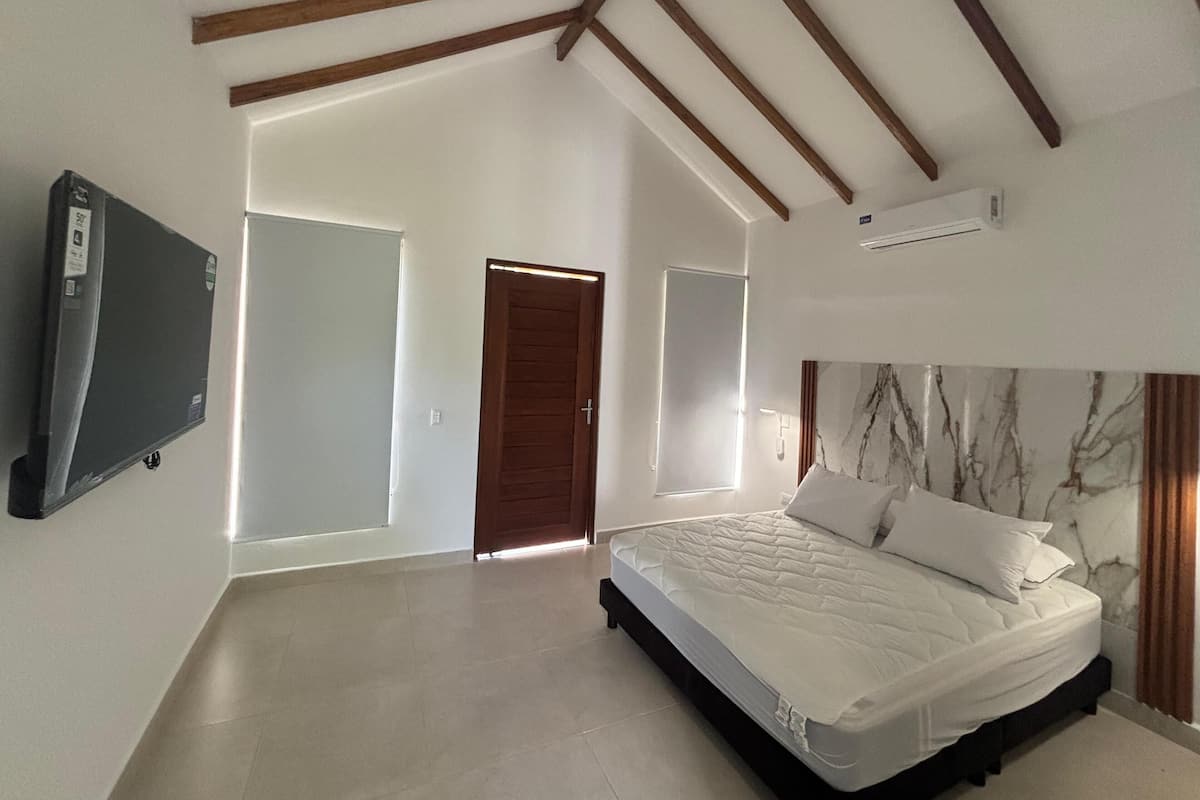 Un dormitorio con cama, televisión y ventilador de techo.