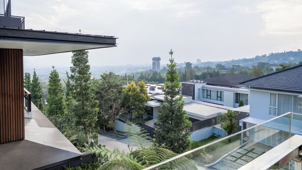 A modern residential area with contemporary houses, a clear sky, and a distant view of a city skyline.