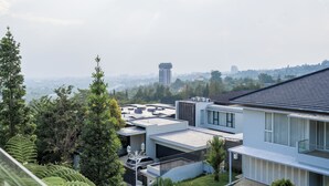 A modern residential building with a flat roof, large windows, and a view of a cityscape in the background.