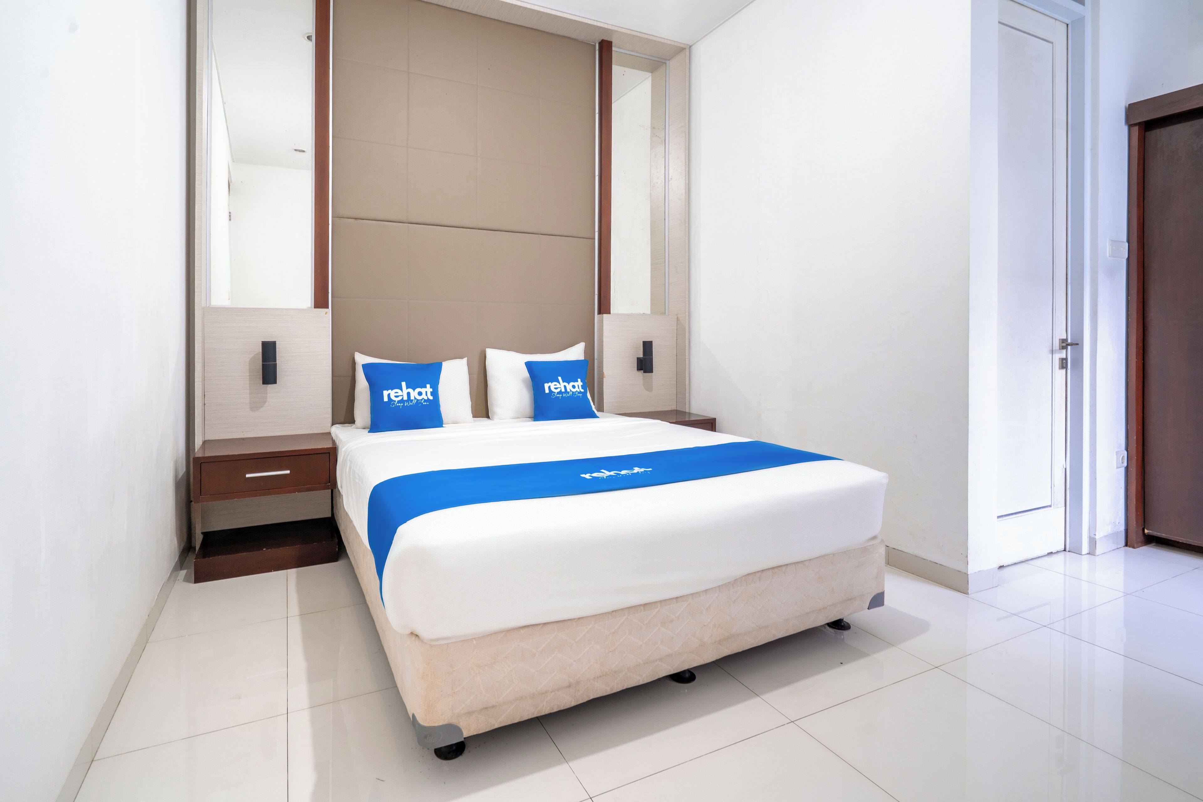 A modern hotel room with a large bed, a nightstand, and a mirror above the bed.