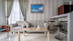A living room with a sofa, a glass coffee table, a framed cityscape painting, and a bar area with stools.