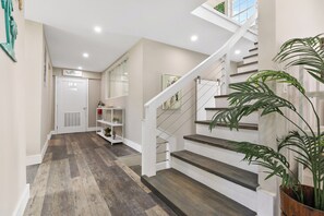 Un intérieur moderne avec un escalier en bois, une porte blanche et un couloir doté d’un plancher en bois.
