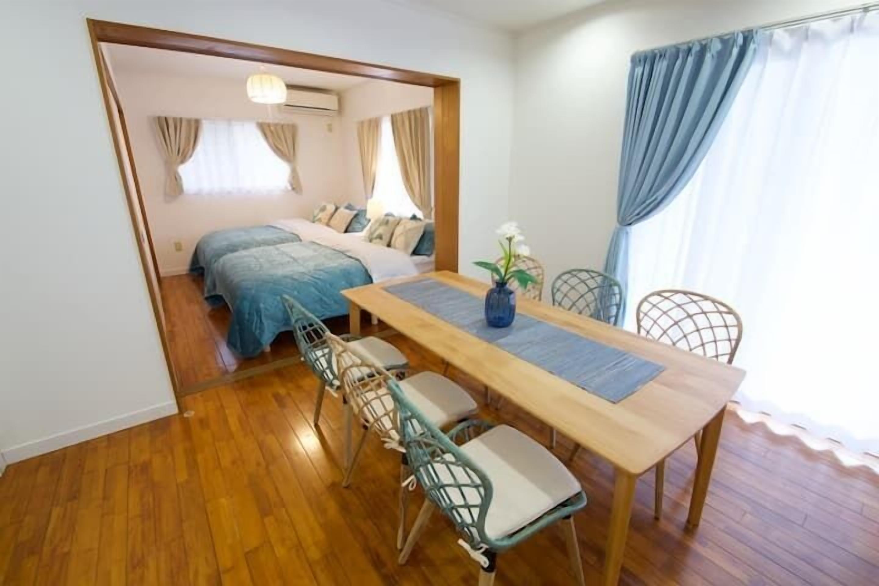 A compact room with a bed, a dining table with chairs, and a small kitchen area.