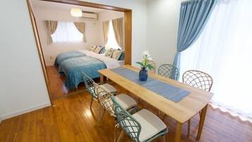 A compact room with a bed, a dining table with chairs, and a small kitchen area.