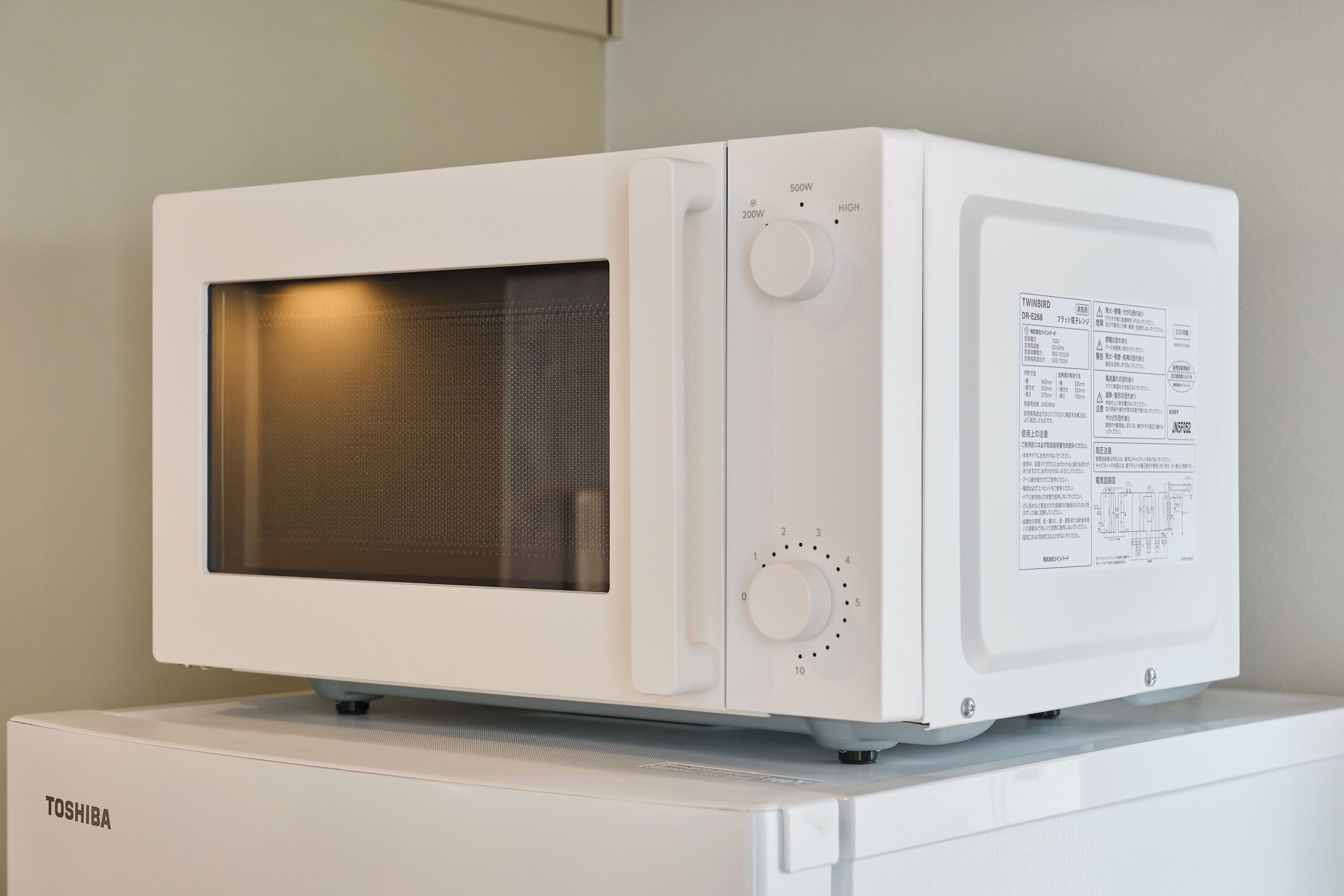Un horno microondas blanco con panel de control y ventana de visualización en el lateral izquierdo.