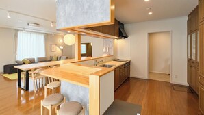 A modern kitchen with wooden countertops, a central island with stools, and built-in cabinets. - Hoshiyado Asahikawa asahimachi (Asahikawa)