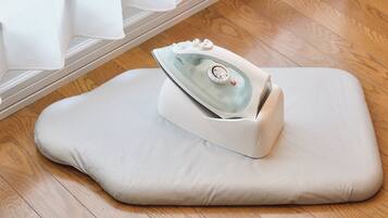 A portable iron on a light-colored cushion on a wooden floor.