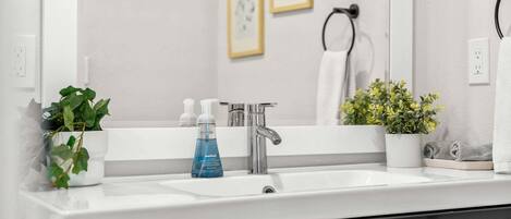 A bathroom with a white sink, a mirror, a towel rack, and two framed pictures on the wall.