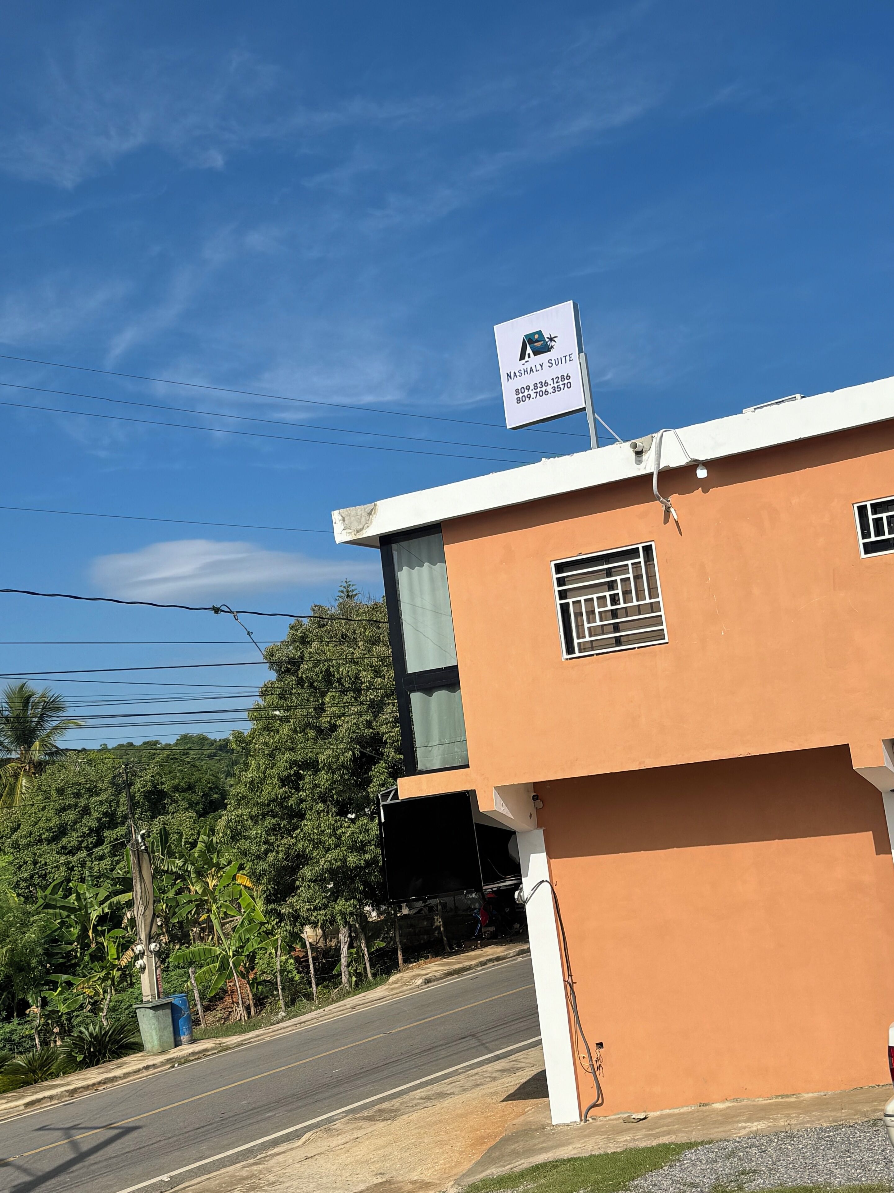 Um edifício com uma placa indicando 'Nashaly Suite' e um céu azul límpido.
