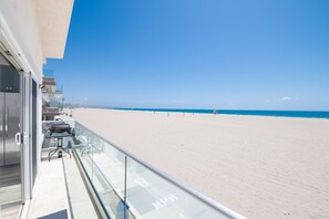 Un balcón con vistas despejadas a una playa de arena y el océano.