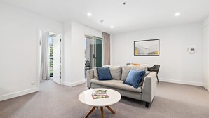 Un salon moderne avec un canapé gris, une table basse ronde et un coin repas comprenant une chaise et une table.