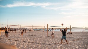 Un match de volleyball de plage se déroule sur un terrain sablonneux, avec un filet et des joueurs.