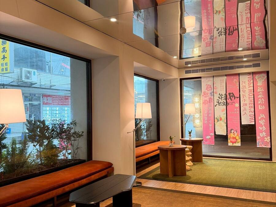 Un interior de varios niveles con vistas al exterior, un área de estar con un banco y banderines decorativos.