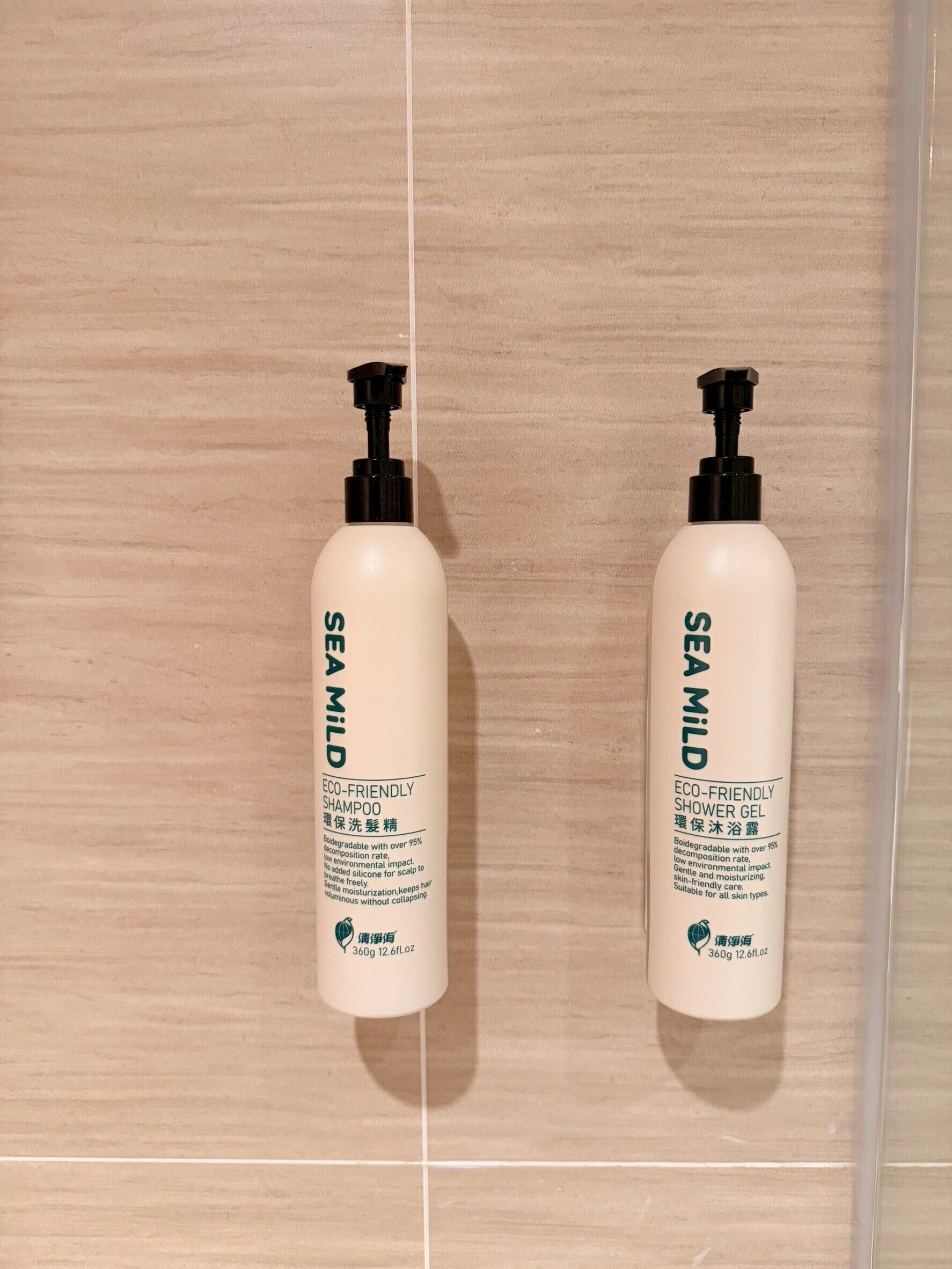 Duas embalagens de shampoo e gel de banho SEA MILD sobre uma parede de azulejos.