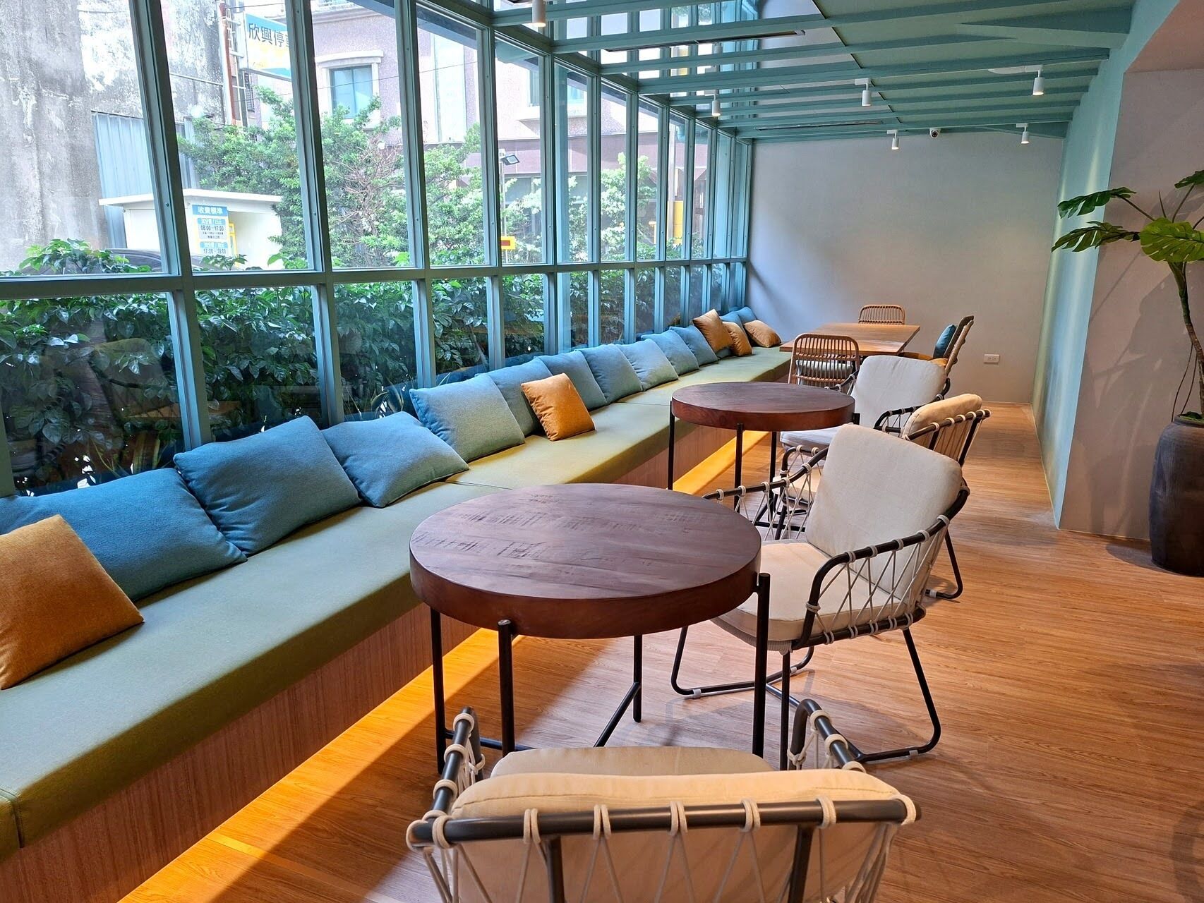 Un interior moderno con una amplia zona de estar acolchada, mesas y sillas de madera.