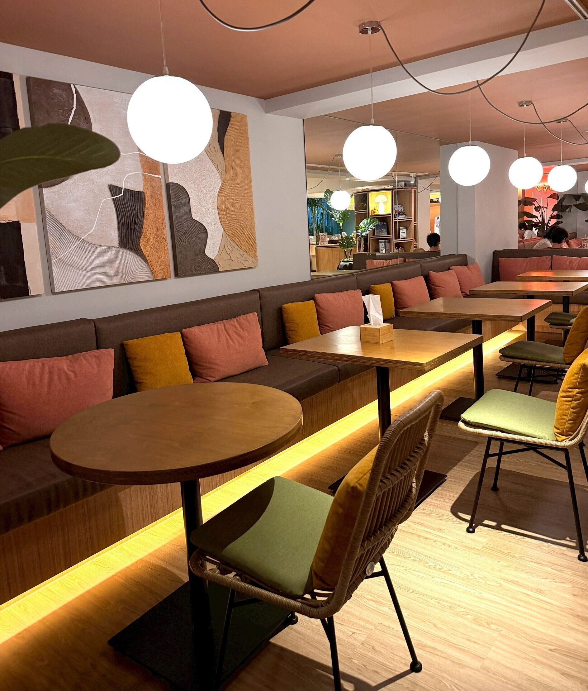 Un interior de restaurante moderno con mesas de madera, asientos acolchados e iluminación colgante.
