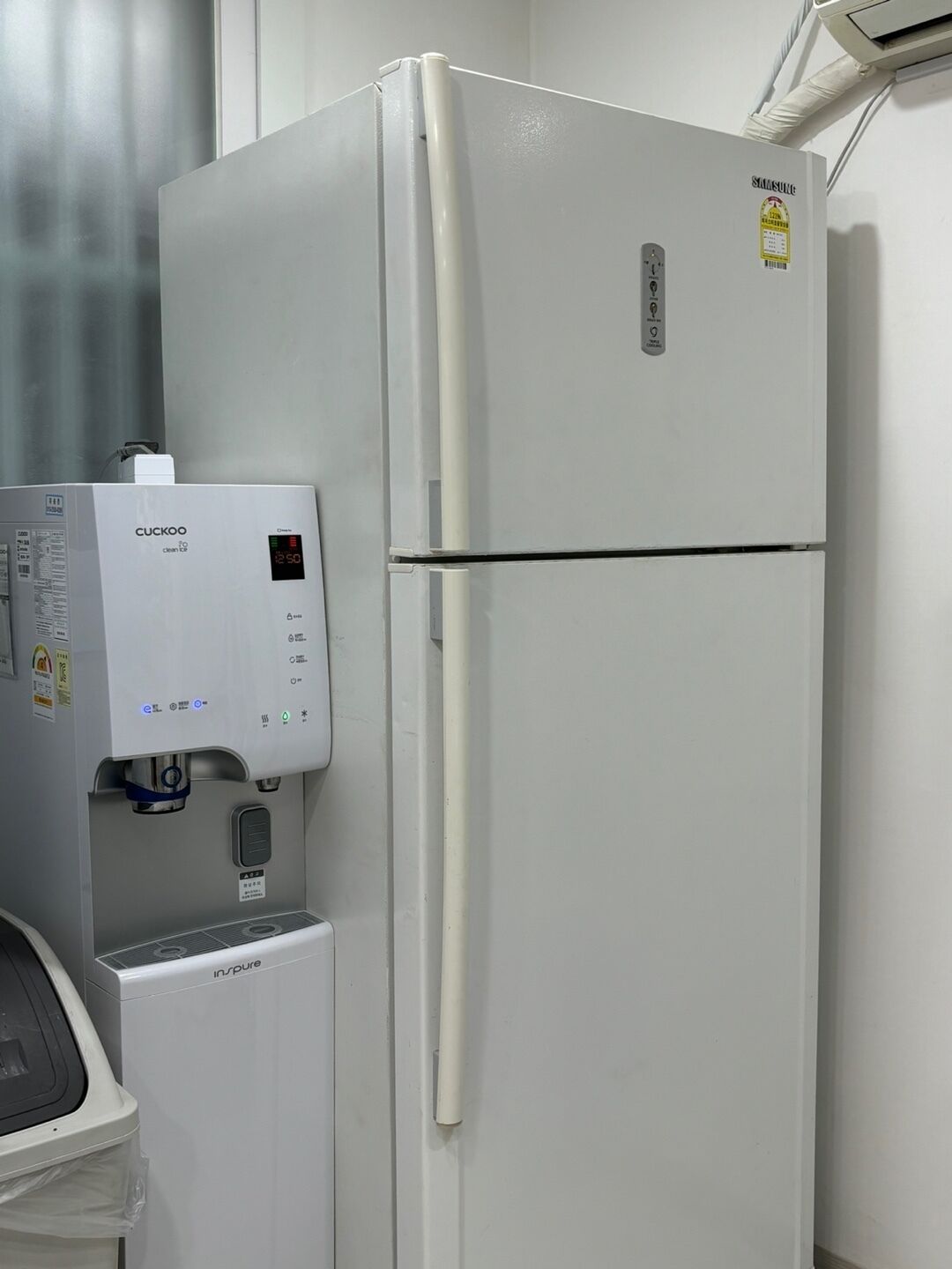 A white refrigerator with a digital display and a water dispenser attached to it.