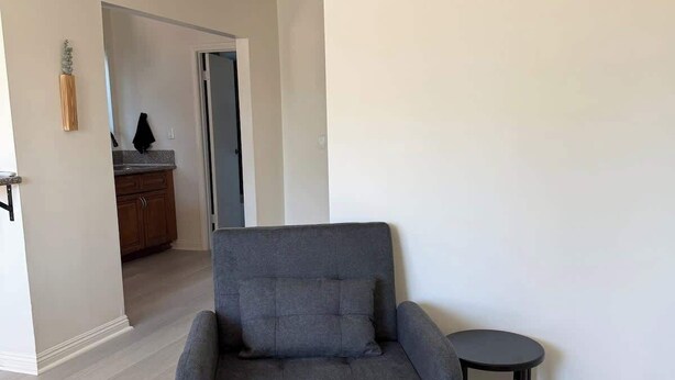 Un soggiorno moderno con un divano grigio, un tavolino rotondo e, sullo sfondo, una zona cucina.