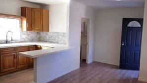 A kitchen with wooden cabinets, a white countertop, and a blue door. - Cozy Home Minutes to Beach Cities! (Paramount)