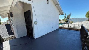 A rooftop with a black surface, a white building with a black door, and a metal fence. - Cozy Home Minutes to Beach Cities! (Paramount)