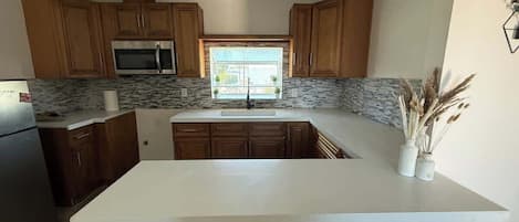 Una cocina con gabinetes de madera, microondas integrado y una isla grande.