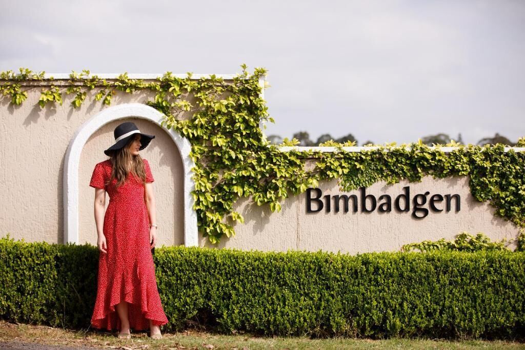A person standing in front of a wall with the name 'Bimbadgen' and greenery.