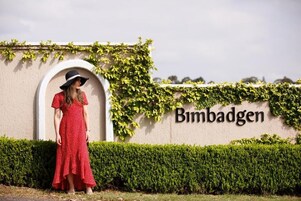 A person standing in front of a wall with the name 'Bimbadgen' and greenery.