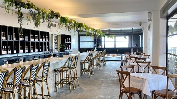 A modern restaurant with a bar area, wooden chairs, and hanging plants. - Bimbadgen Estate (Pokolbin)