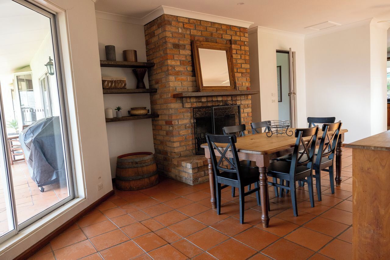 Un comedor con chimenea de ladrillo, mesa de madera y sillas.