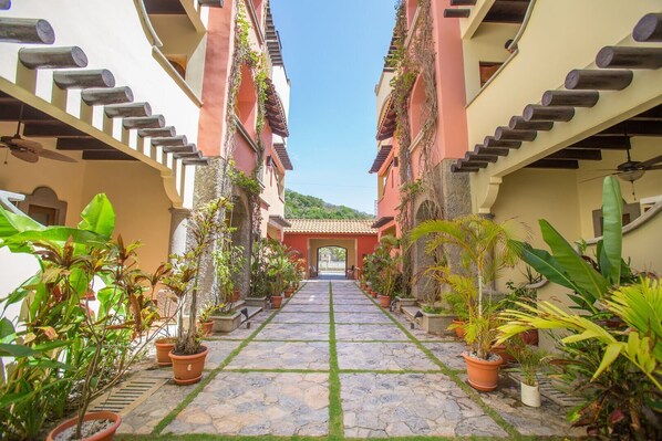 A courtyard with a stone pathway, potted plants, and buildings with balconies. - Mermaid’s Hideaway—2 bedroom, 2 bath
3 minute walk to stunning West Bay Beach (West Bay)