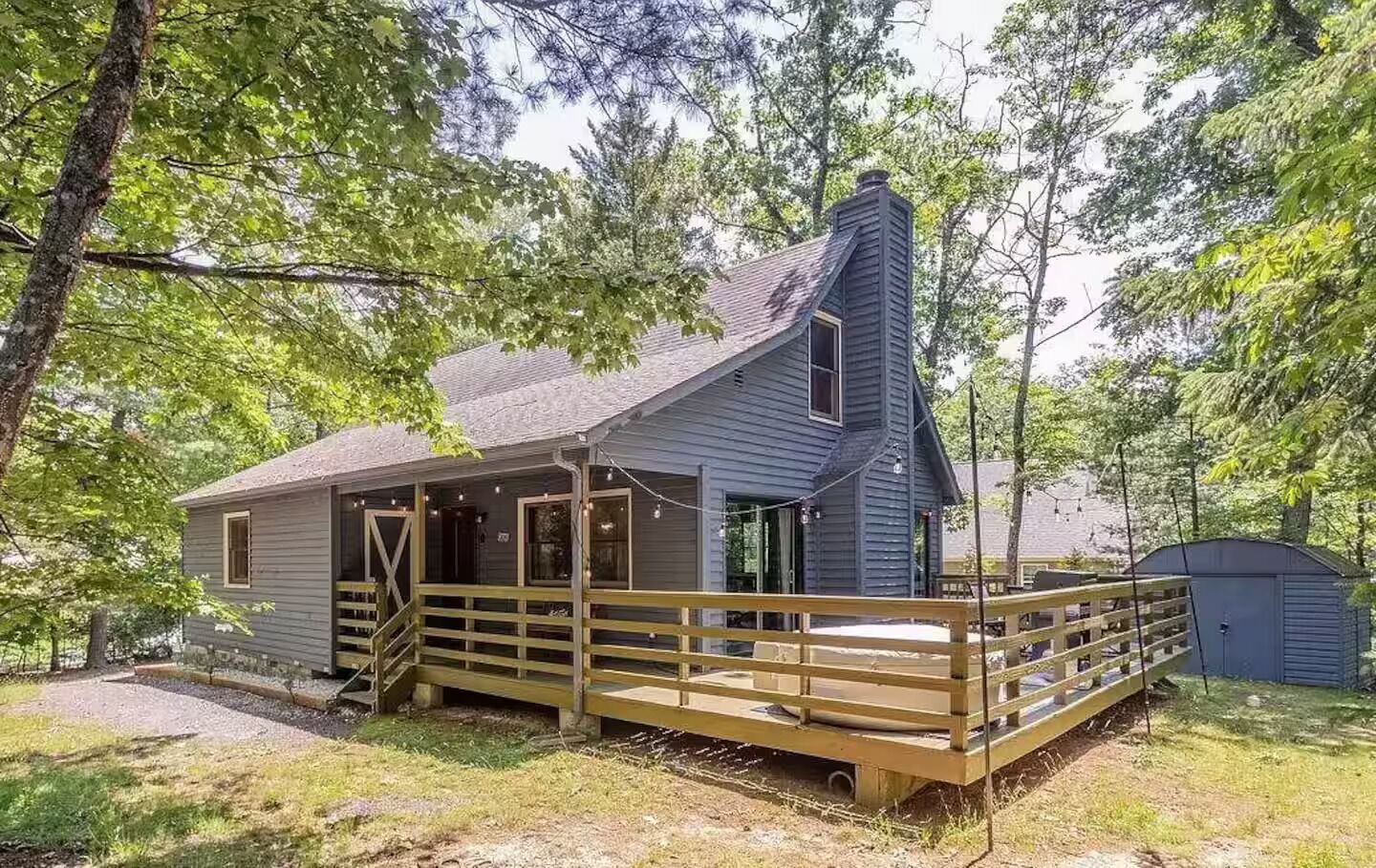 Une cabane avec une terrasse en bois, une cheminée et un porche.