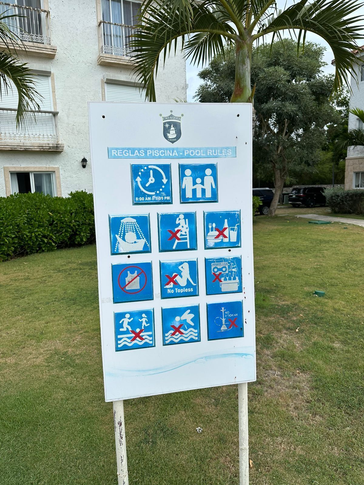 Señal con las normas de la piscina: horario de funcionamiento, prohibido topless, prohibido topless, prohibido bucear y prohibido nadar.