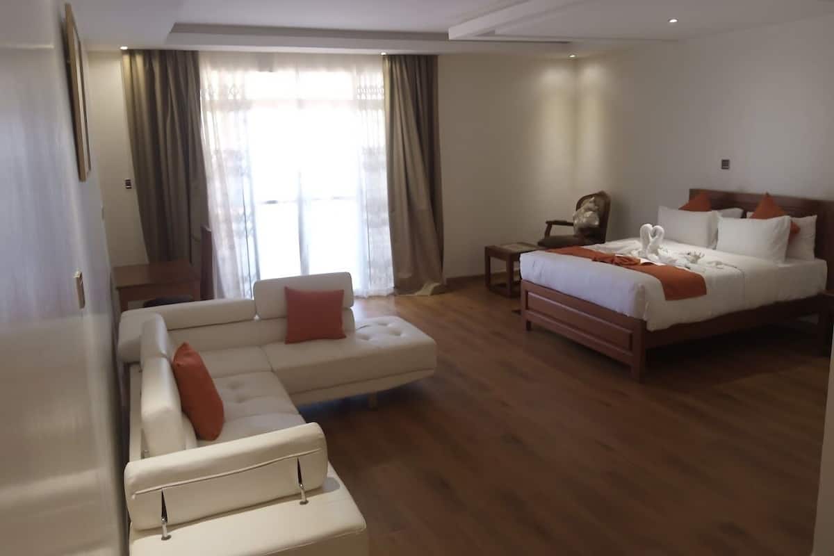 Una habitación de hotel con una cama grande, un sofá, una mesita y una silla.