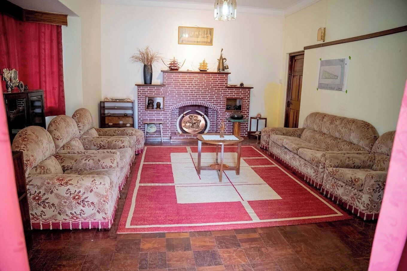 A living room with a brick fireplace, two sofas, a coffee table, and a red rug.