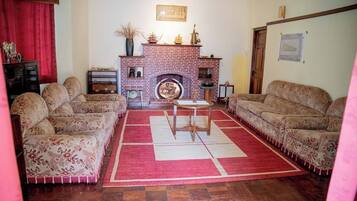 A living room with a brick fireplace, two sofas, a coffee table, and a red rug.