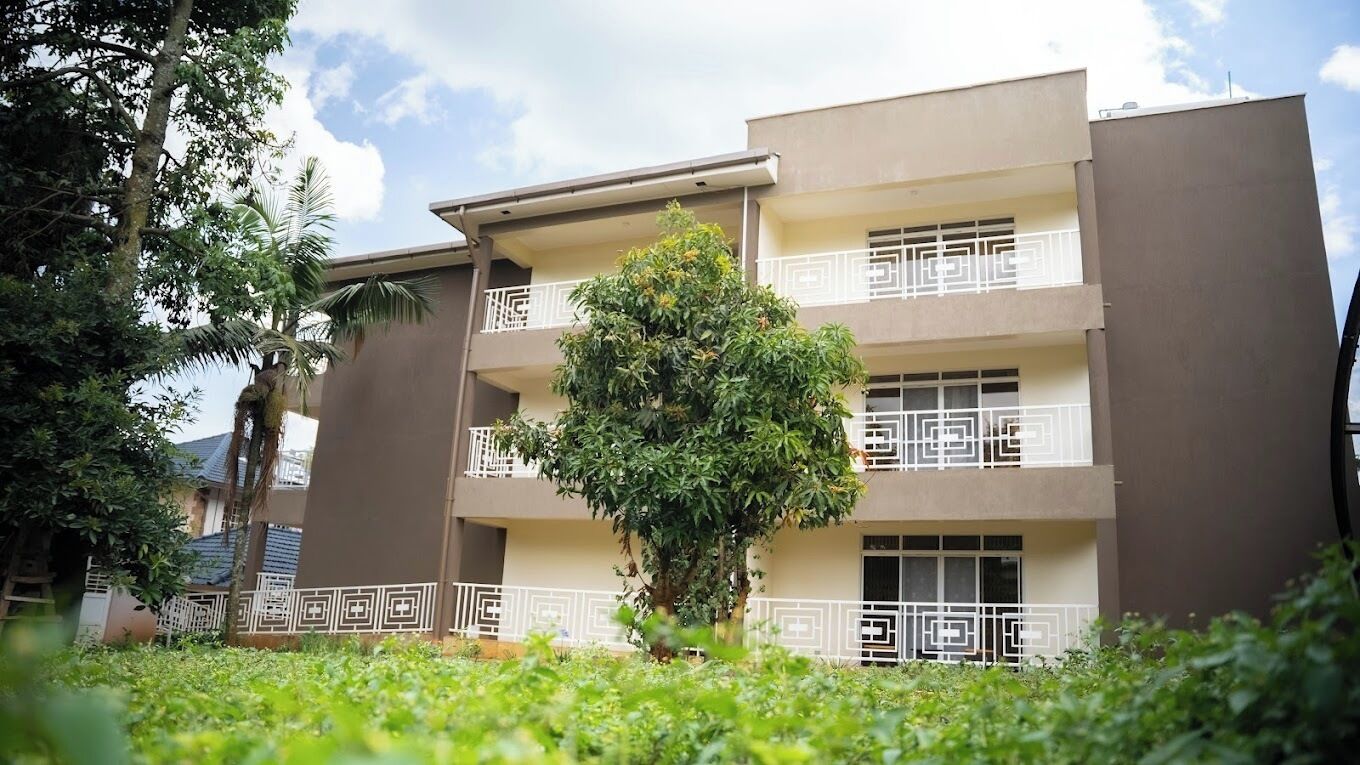 A multi-story residential building with balconies, surrounded by greenery.