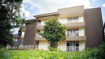 A multi-story residential building with balconies, surrounded by greenery.