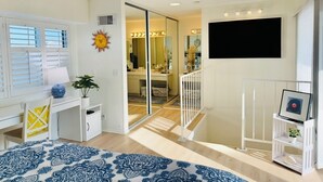 A modern bedroom with a bed, a desk, and a large window with blinds. - Ocean view, updated bright & relaxing beach condo close to it all! (Oceanside)