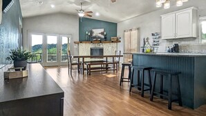 Une cuisine spacieuse dotée d’un îlot central, de planchers en bois et d’un ventilateur de plafond.