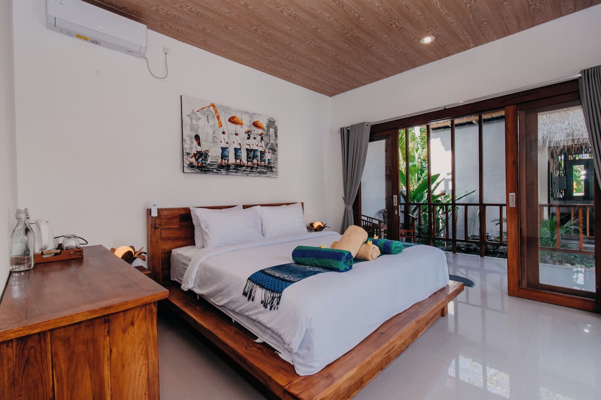 Un dormitorio con una cama de madera, un cuadro en la pared y vistas al exterior a través de una puerta corrediza.